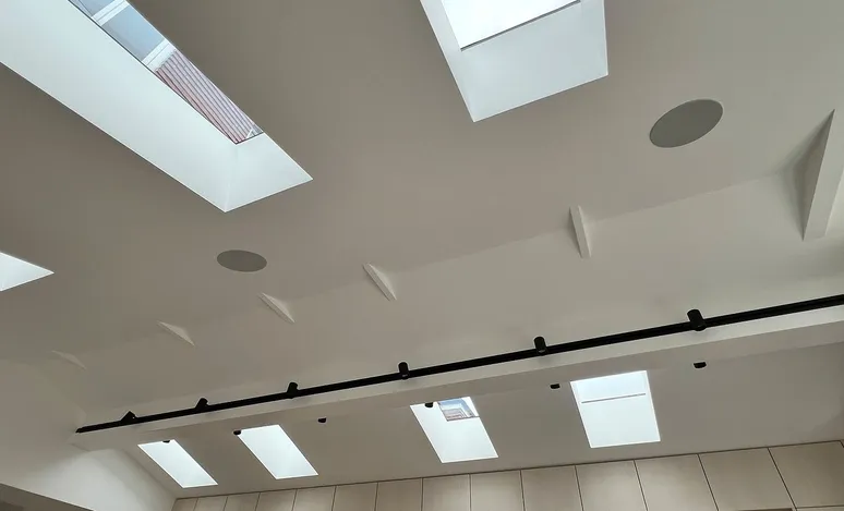 photo of ceiling in a modern home, with 8 skylights, two round speakers in the white ceiling.