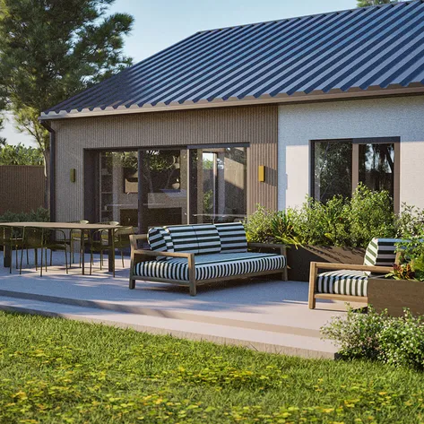 A modern outdoor patio area adjacent to a single-storey house with a sleek metal roof. The patio features stylish striped cushioned chairs and a dining table with black chairs.