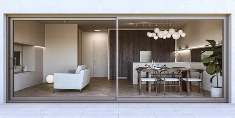 Interior view through a sliding patio door with a dark wood dining table, white sphere lighting, and a comfortable sofa.