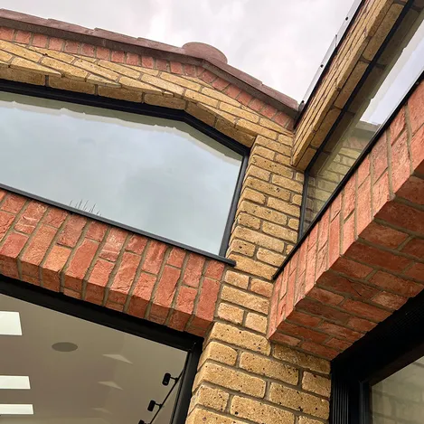 Close up of black window frames on the corner of a yellow and red brick house showing off its blend of traditional and modern design features.