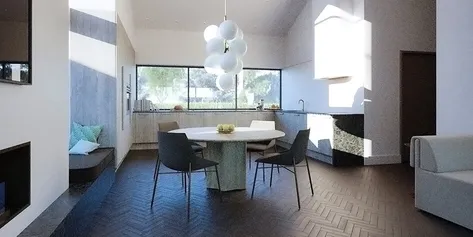 A spacious interior kitchen and dining area, with a large circular dining table, modern black chairs, and a sculptural bubble chandelier, illuminated by natural light from large windows.